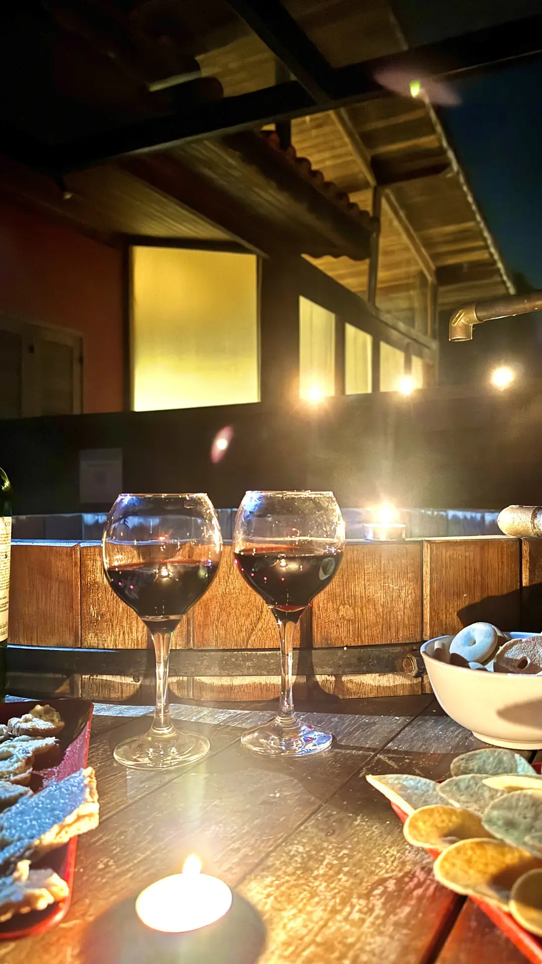 Mesa de madeira posta ao lado do ofurô aquecido, à noite, com o vale escuro ao fundo
