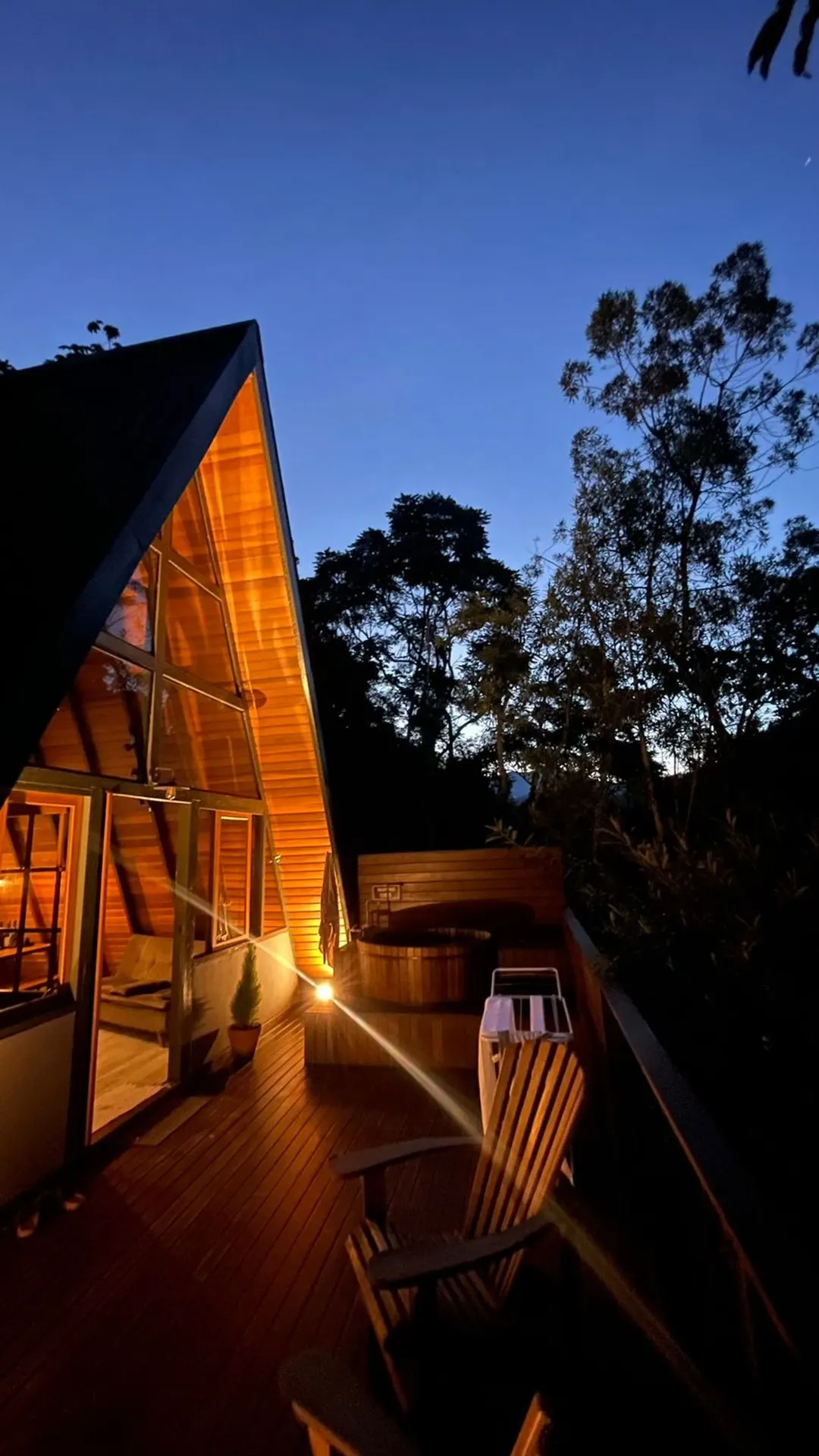 A Cabana Solaris ao anoitecer, com luz quente acesa e o ofurô no deck
