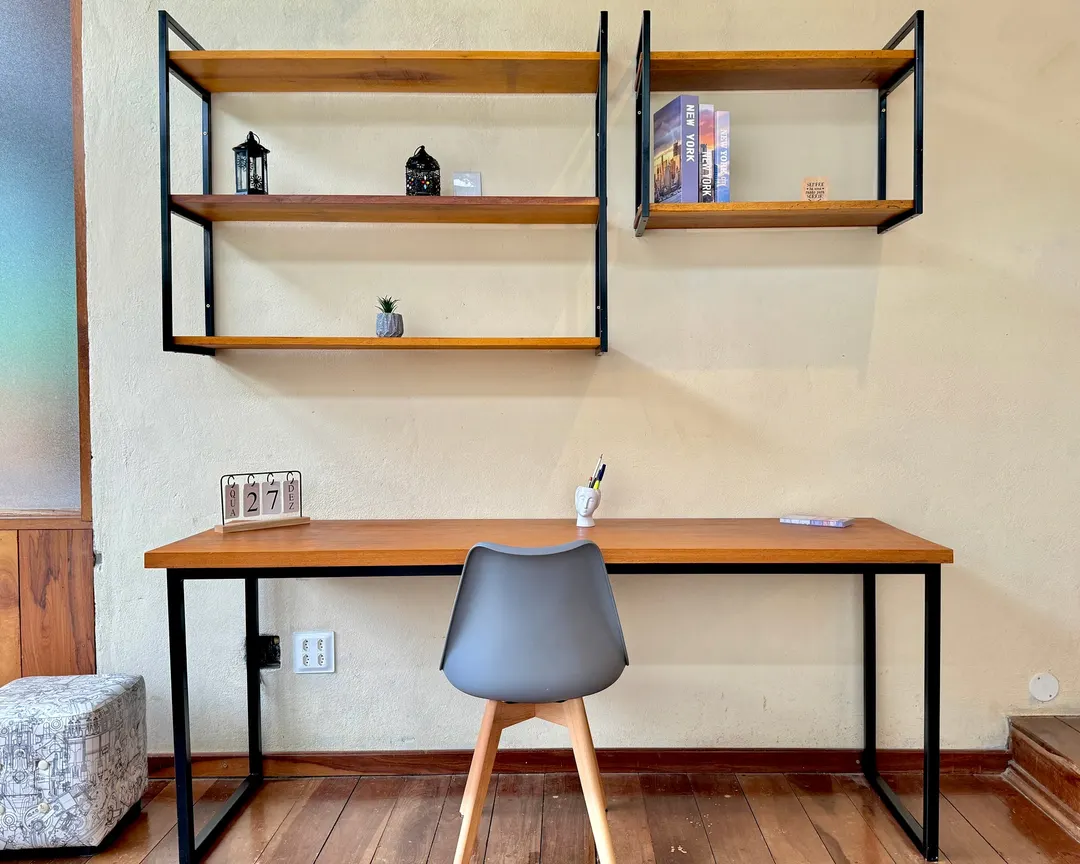 Escritório envidraçado do Studio Lua Nova, com mesa de trabalho e estantes de madeira